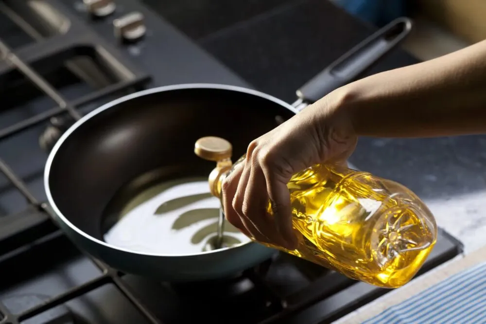 Đổ dầu ăn vào chảo nóng để chiên cá