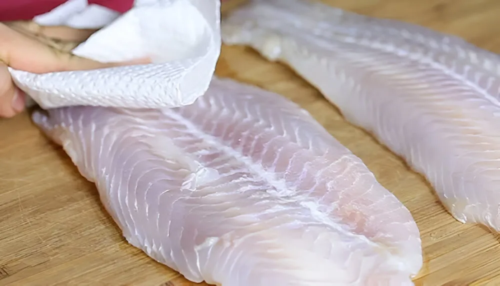 Thấm khô cá bằng khăn giấy để tránh bắn dầu khi chiên